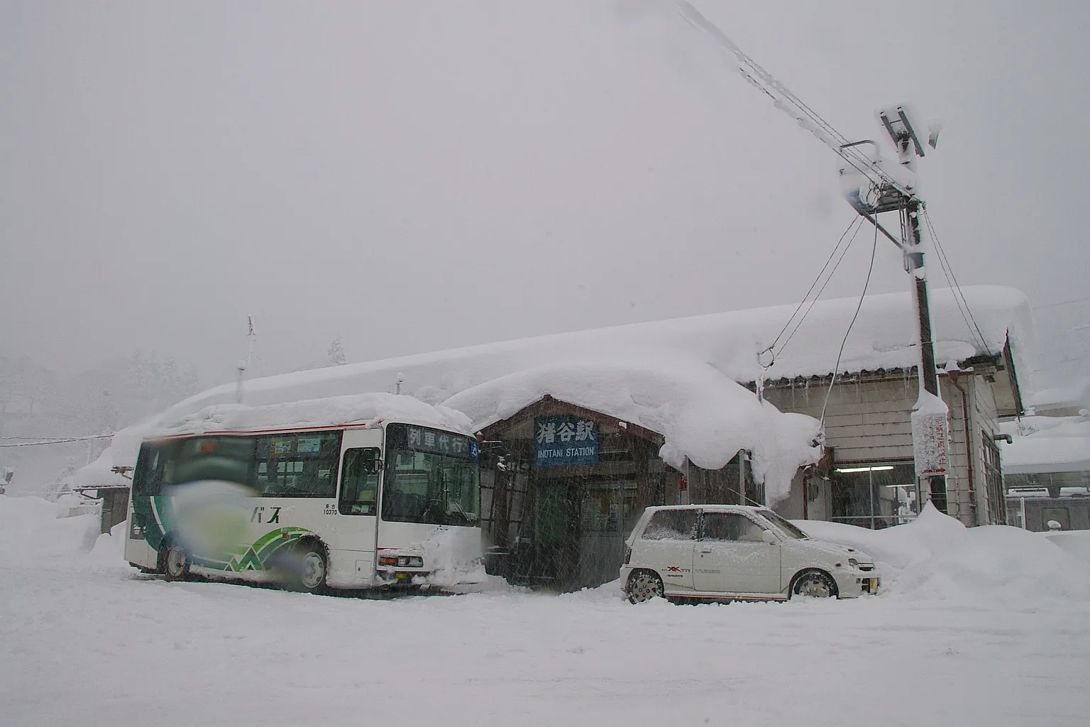 Inotani Station on a day of heavy snow, with a rail-replacement bus waiting for passengers. Photo: Takasunrise0921(talk / Contributions) at the Japanese Wikipedia (CC BY-SA 3.0)