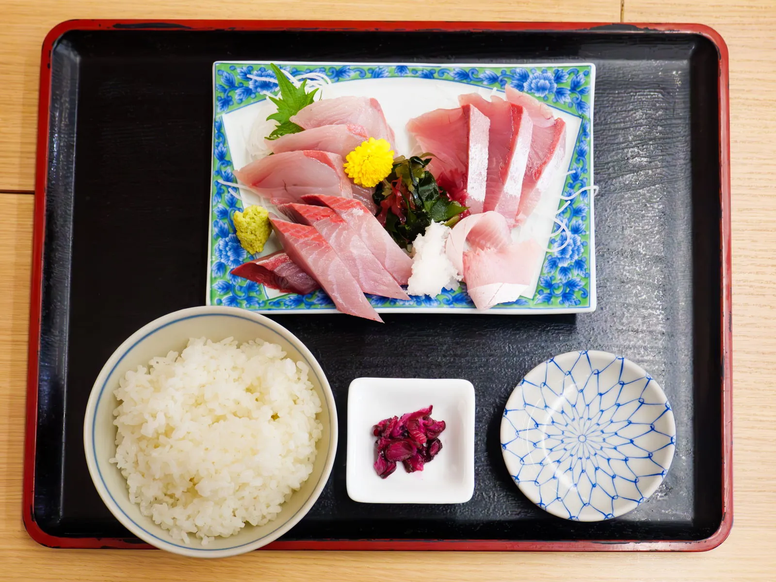 A buri sashimi set. Fat in the belly cuts, firmness in the back — one fish, two expressions. Photo: くろふね (CC BY 4.0)