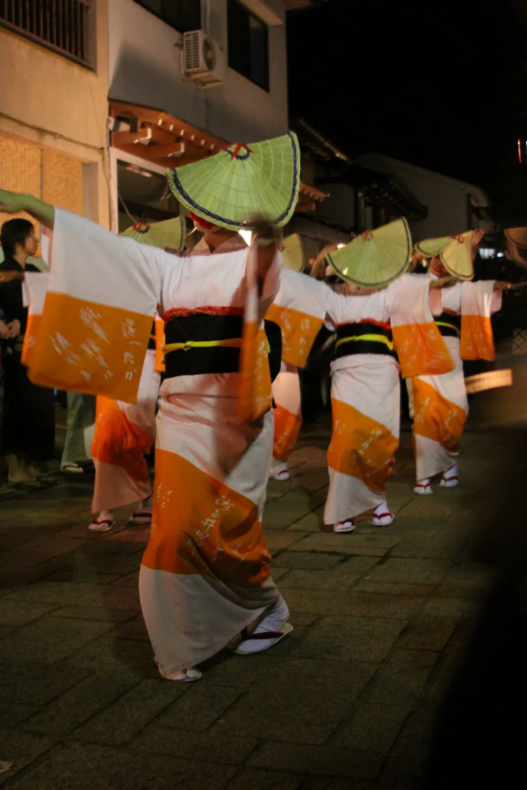 A line of dancers in amigasa (woven straw hats) moves down the stone-paved street in the night machinagashi. Photo: JohnNewton8 (CC BY-SA 4.0)