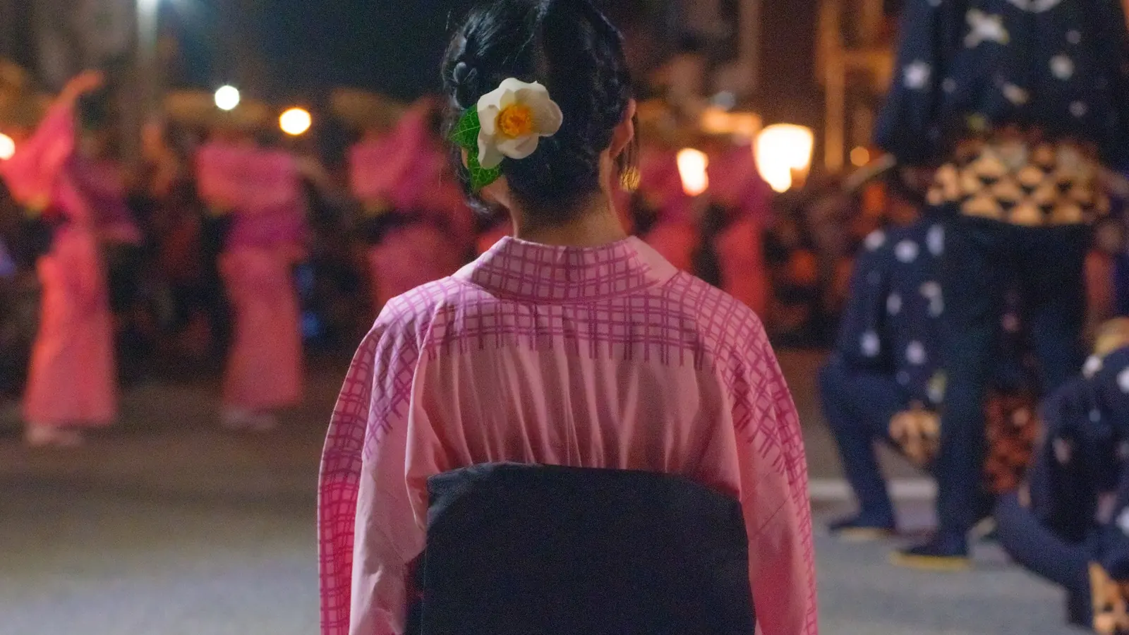 流しの合間、路上に膝をつく踊り手。髪に白い花