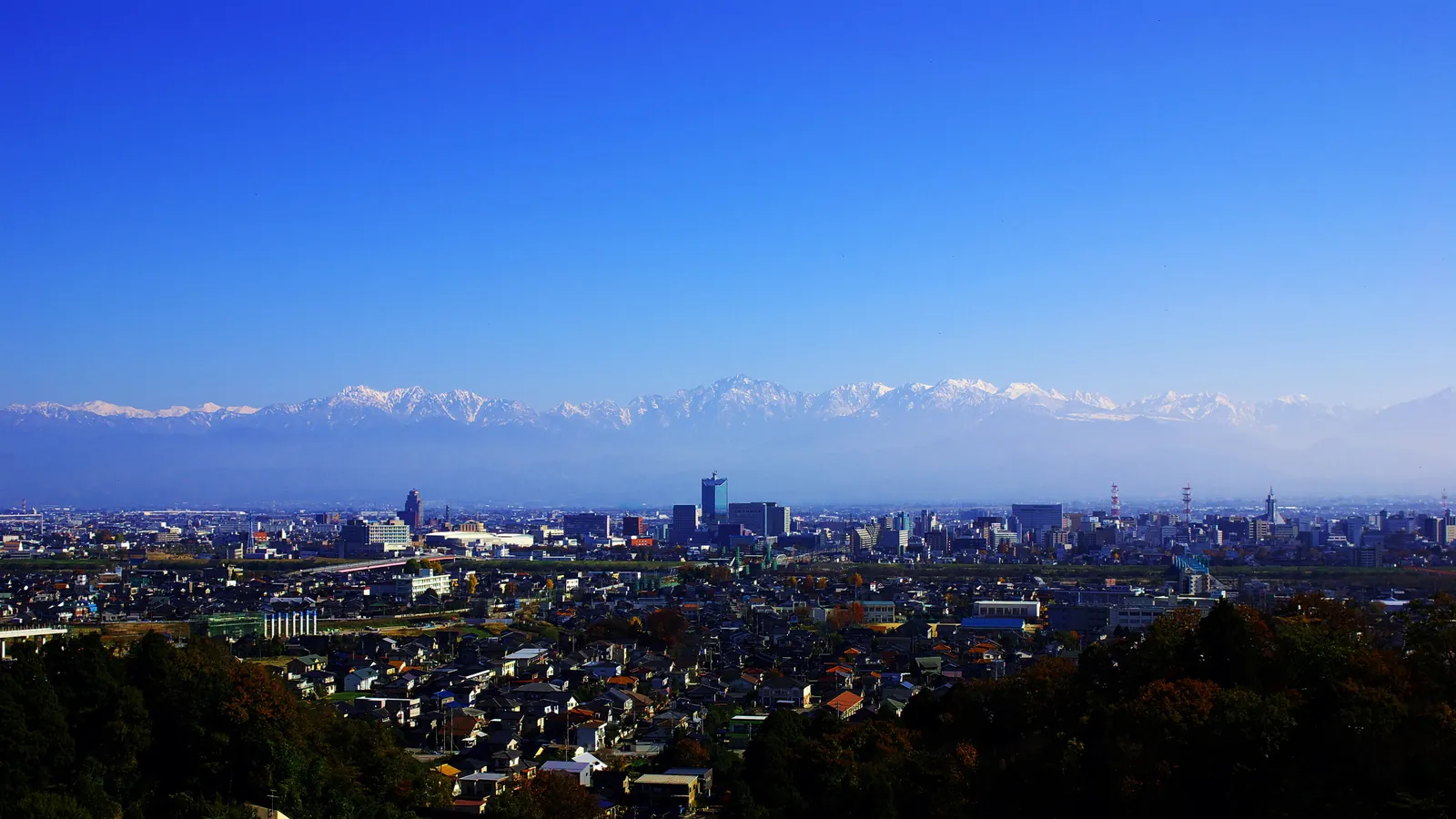 The Tateyama mountain range rising beyond the city of Toyama. Photo: 名古屋太郎 (CC BY-SA 3.0)