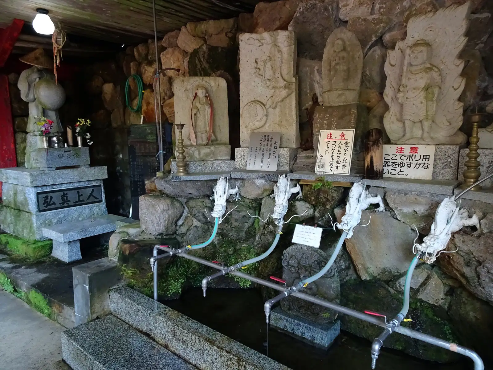 The sacred spring of Anantan, where people come without pause to draw water at the mouth of the rock grotto. Photo: ブルーノ・プラス (CC BY 4.0)